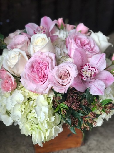 Flower Arrangement of garden roses, orchids and hydrangea in a rustic wood box. 