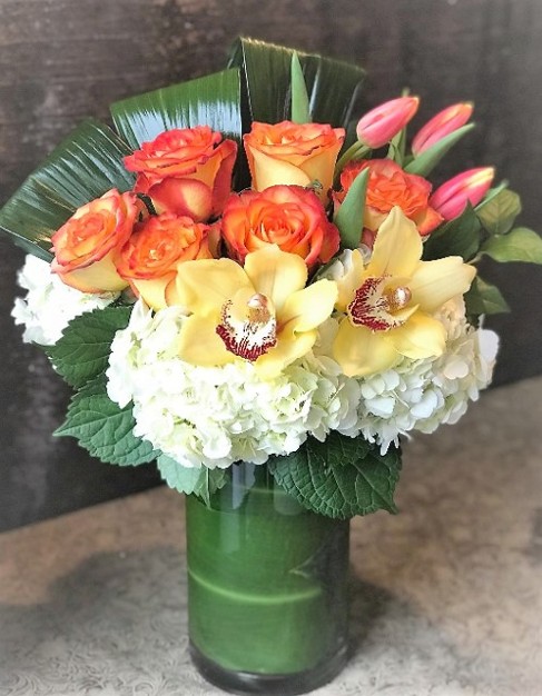 Tall Glass Vase filled with bright and cheery flowers, tulips, roses and orchids