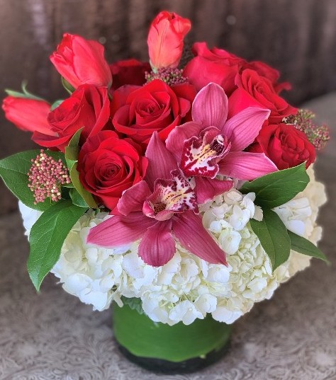 medium red rose arrangement in low glass vase. 